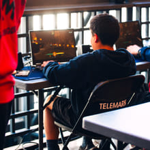 Ungdommer i e-sport-stoler følger med på noe foran dem i et moderne undervisningsrom.