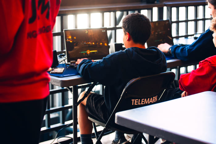 Ungdommer i e-sport-stoler følger med på noe foran dem i et moderne undervisningsrom.
