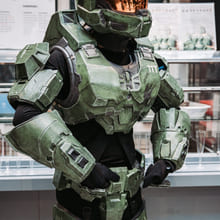 En person utkledd i grønn rustning, inspirert av science fiction eller gaming, poserer innendørs.