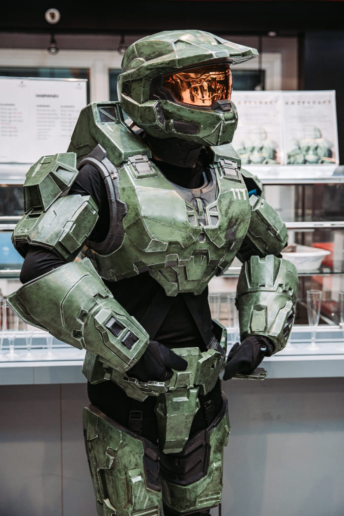 En person utkledd i grønn rustning, inspirert av science fiction eller gaming, poserer innendørs.