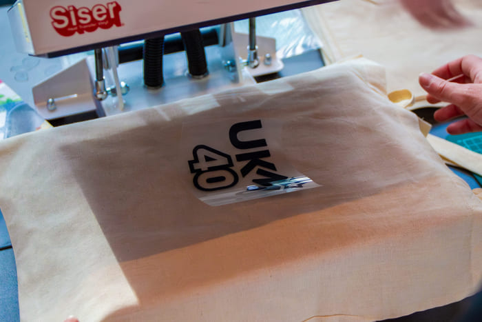 Et stykke stoff blir dekorert med trykk av et motiv i en kreativ håndverksaktivitet.