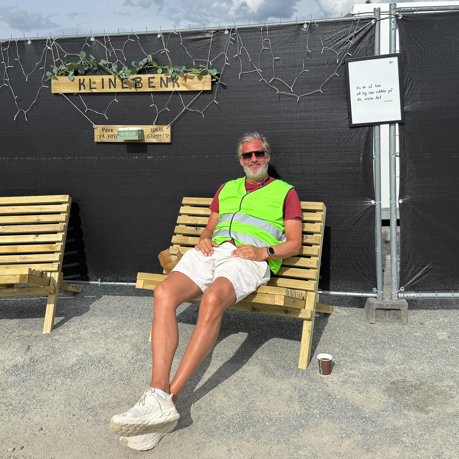 Mann sitter på benk ved skiltet "Klinebenk".