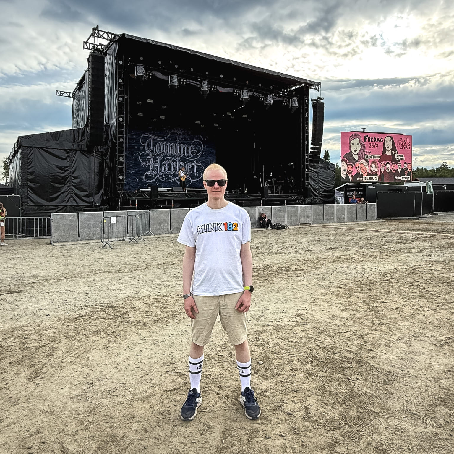 Ung mann står alene foran hovedscenen på festivalområdet.