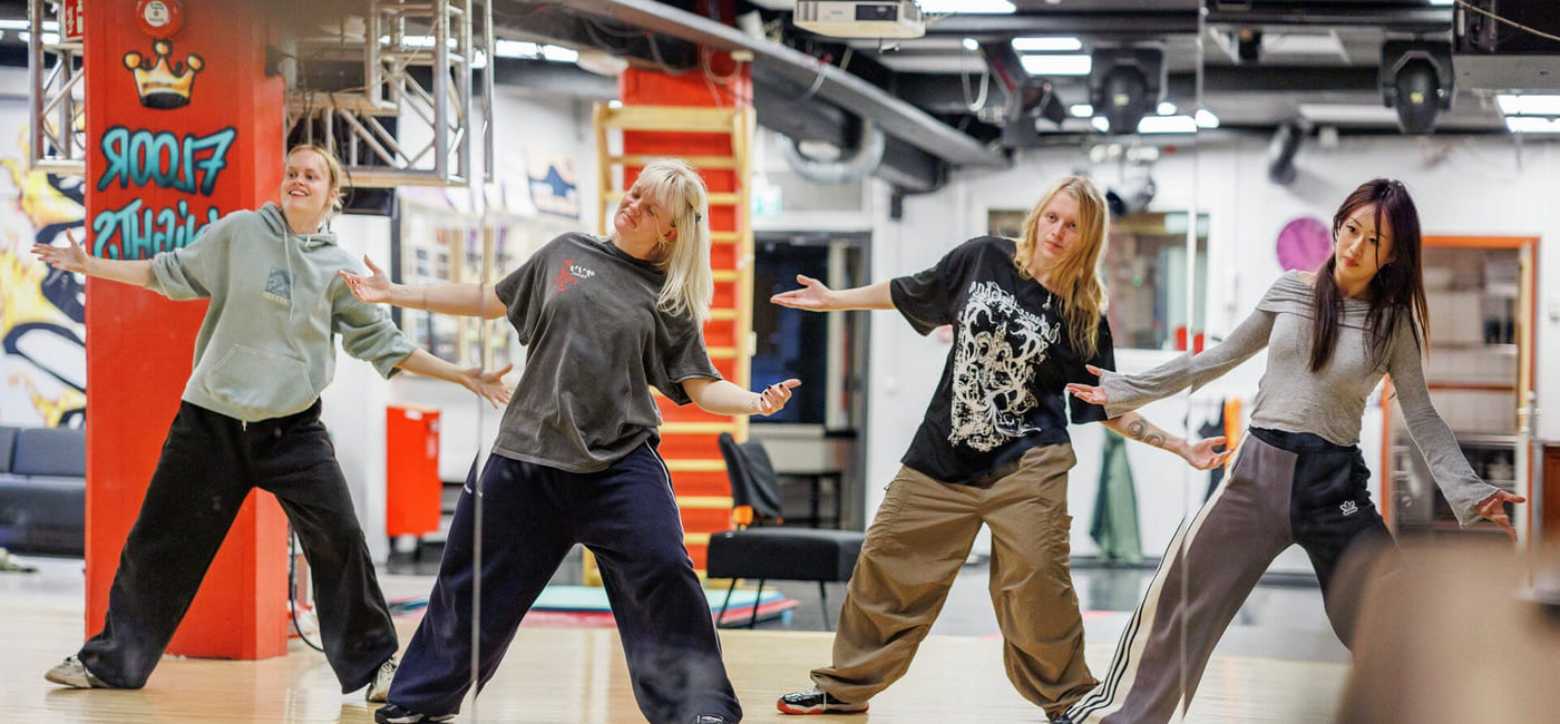 Fire jenter danser i et dansestudio. De har på seg avslappede klær.