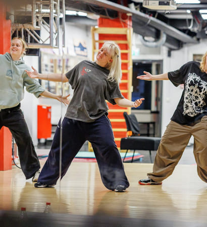 Fire jenter danser i et dansestudio. De har på seg avslappede klær.