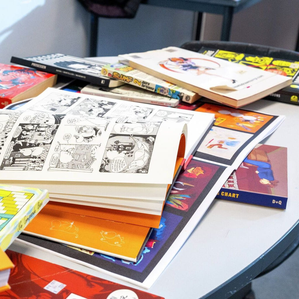 En haug bøker og tegneserier på et bord.