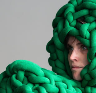 En dame ser til venstre. På hodet og foran seg har hun irrgrønne tau.