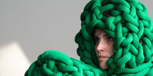 En dame ser til venstre. På hodet og foran seg har hun irrgrønne tau.