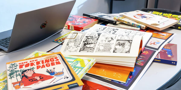 En haug bøker og tegneserier på et bord.