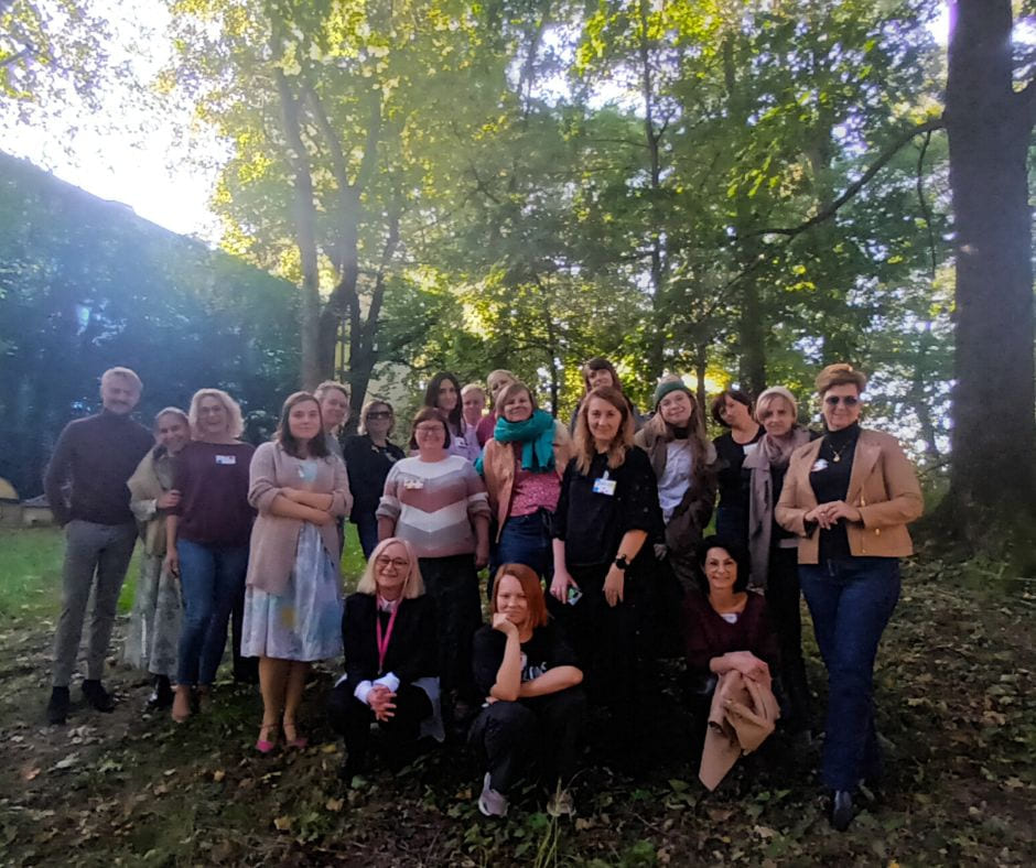 Gruppe mennesker samlet utendørs i park med trær og grøntområder i bakgrunnen.