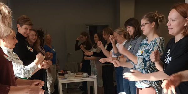 Gruppe deltar i en aktivitet rundt bord med materialer i et innendørs rom.