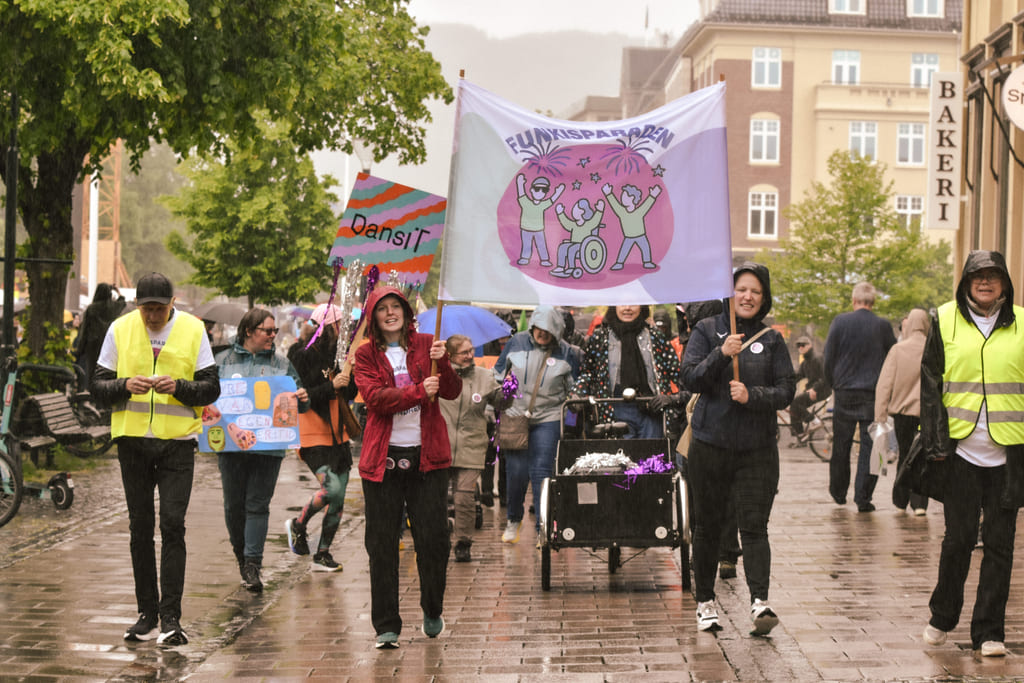 Gruppe mennesker som går i parade med banner i bygate