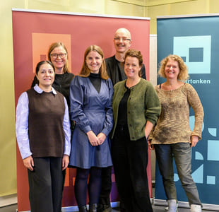 Gruppebilde av fem personer. De står foran tre fargrike roll-ups i Kulturtankens farger.