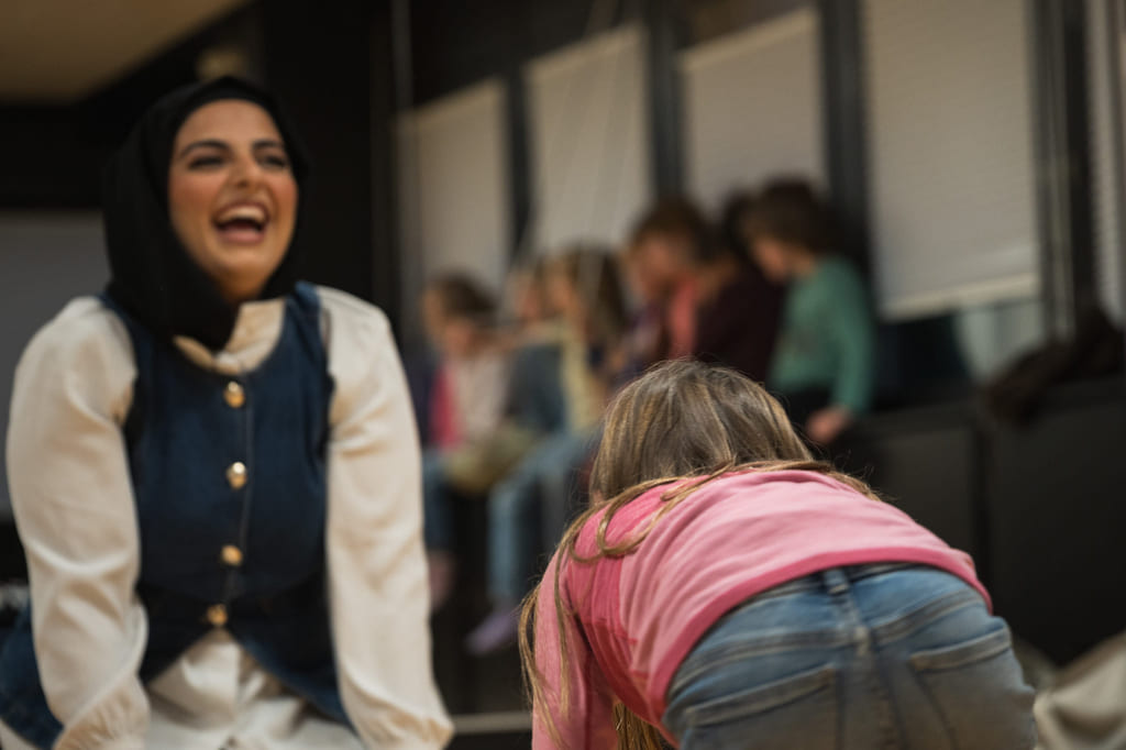 En dame ler mens en jente krabber mot henne.