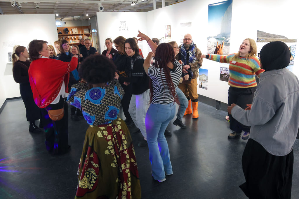 Mennesker danser i et utstillingsrom med fargerik dekor og kunstinstallasjoner.