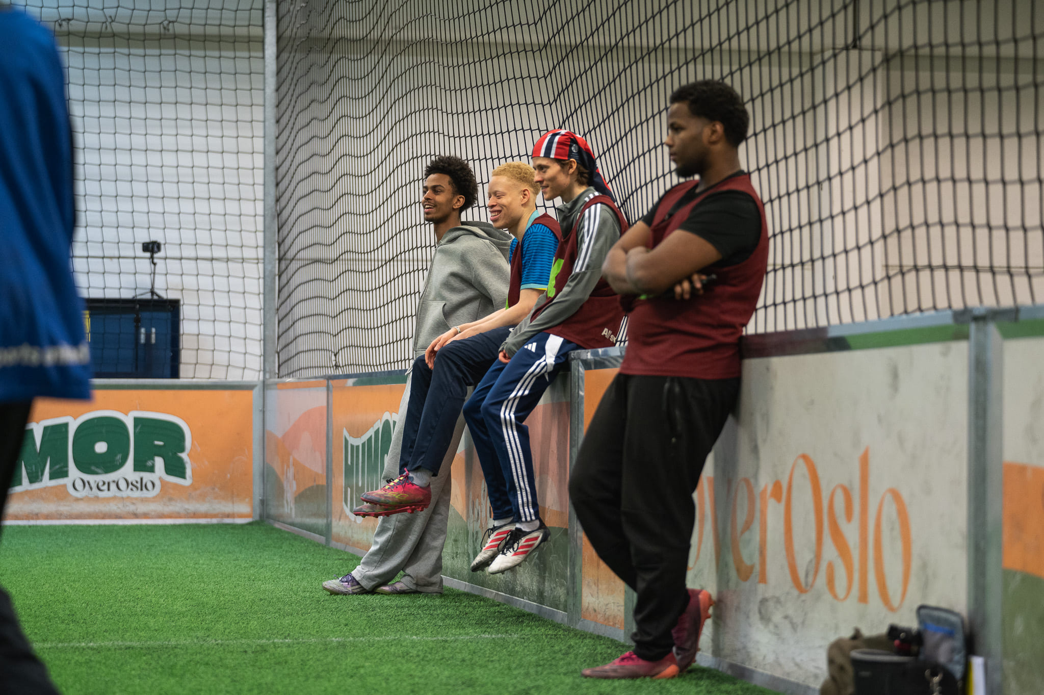 Fire unge menn ikledd sportstøy ser mot venstre. De er i en cageball-binge.