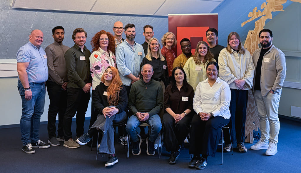 Gruppebilde av personer som stor og sitter foran et kart av Norge i tre og en roll-up med Kulturtankens logo.