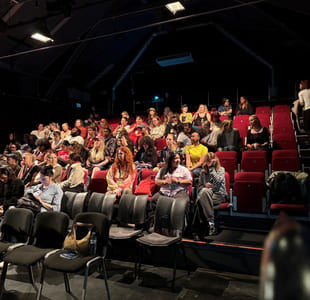 Deltakere på en konferanse sitter klare i salen like før den starter.