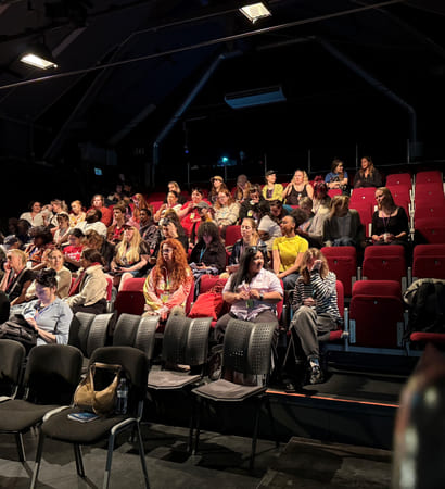 Deltakere på en konferanse sitter klare i salen like før den starter.