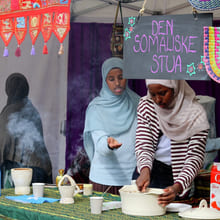 To somaliske kvinner i hijab serverer mat på kulturboden Den Somaliske Stua med stigende damp.