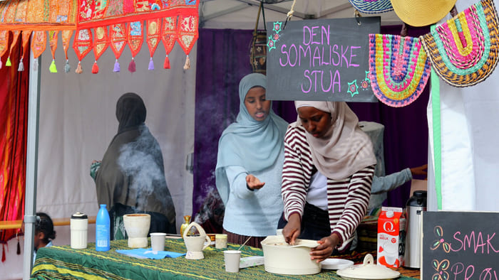 To somaliske kvinner i hijab serverer mat på kulturboden Den Somaliske Stua med stigende damp.