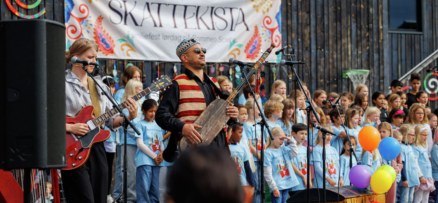 En fargerik parade med folkemengder samlet langs gaten, med et banner over hodet.