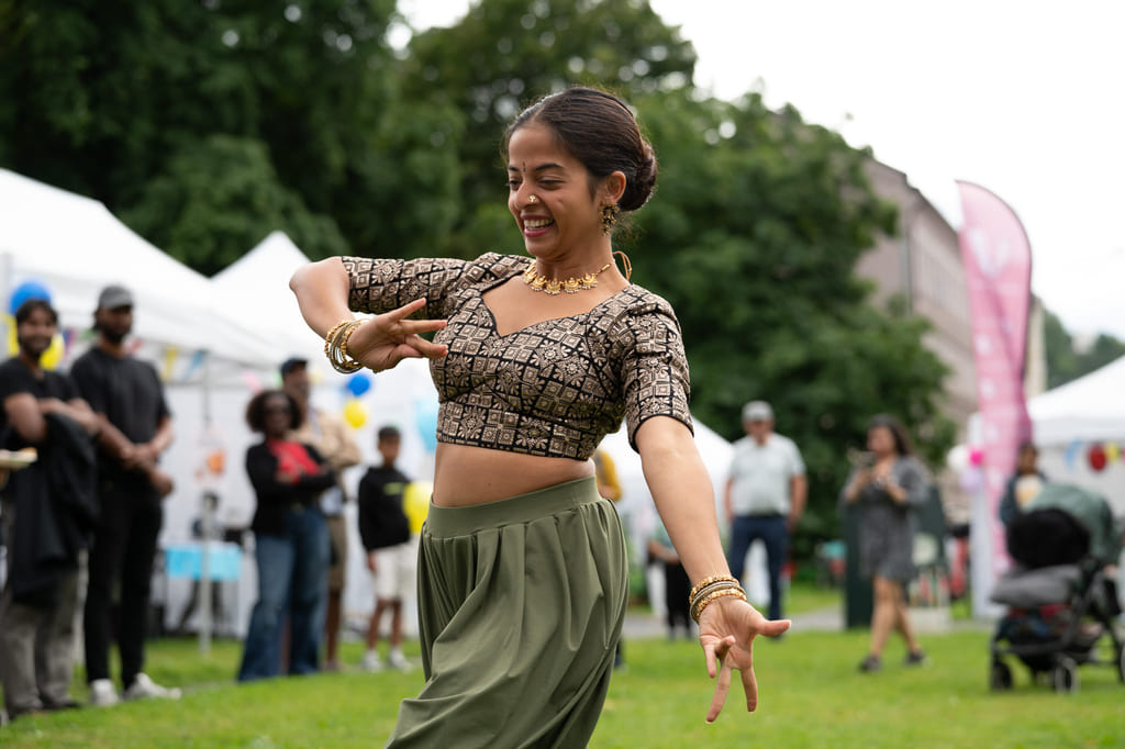 En person danser på en gressplen under et utendørsarrangement.