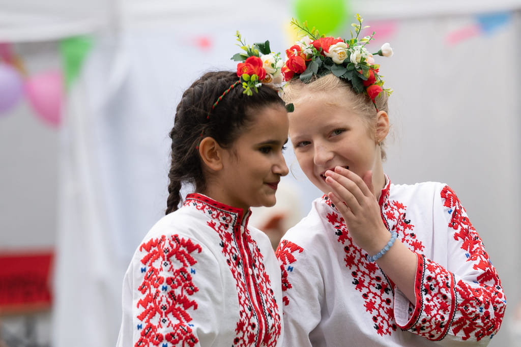 To personer med blomsterkranser og mønstrede klær står tett sammen.