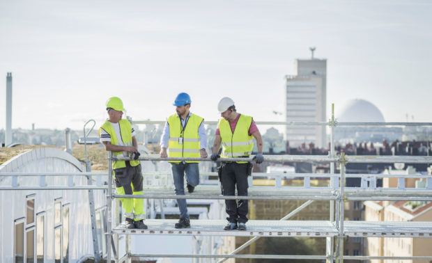 Tre menn på stilas på byggeplass