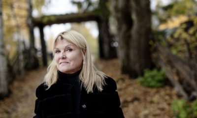 Blond kvinne, rundt 60 år, på et høstlig tun.
