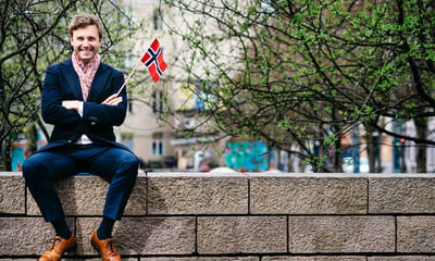 Mangfold: Blid mann sitter på en mur med norsk flagg i hånden.