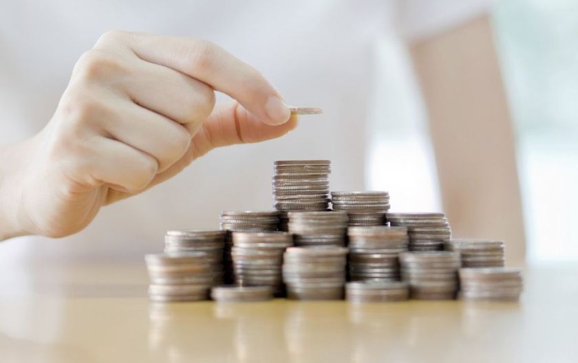 Her ser du en hånd som løfter ett kronestykke på et tårn av andre kronestykker.