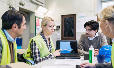 Agilt: En gruppe kolleger sitter rundt et bord med en PC, to kvinner og to menn.