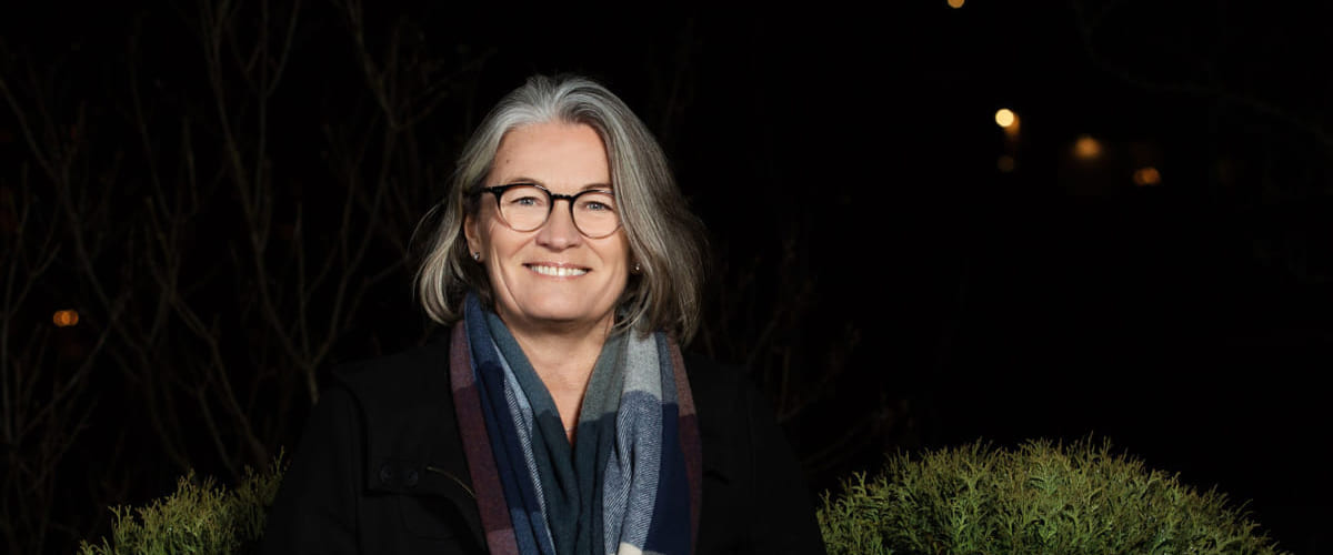 Mindfulness: Blid dame står utendørs med et skjerf rundt halsen.