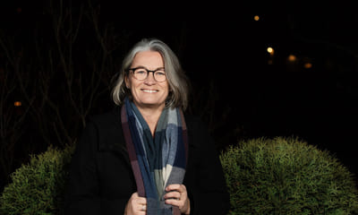 Mindfulness: Blid dame står utendørs med et skjerf rundt halsen.