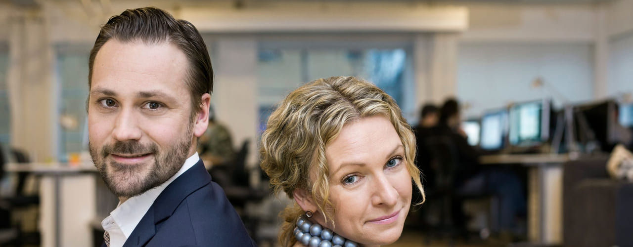 Personligheten: En mann og en kvinne sitter rygg mot rygg og ser i kameraet.