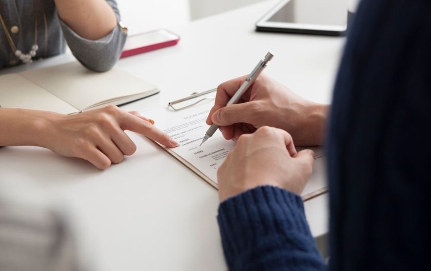 Hendene til to personer som signerer et dokument. Illustrasjon til sak om saksbehandlingsregler og varsling