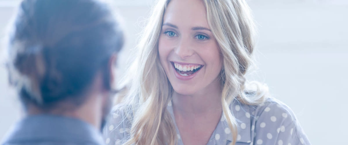 Kvinne med blondt hår smiler til mannlig kollega. Illustrasjon til sak om å lykkes med HR for Lederne