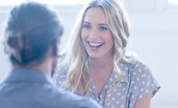 Kvinne med blondt hår smiler til mannlig kollega. Illustrasjon til sak om å lykkes med HR for Lederne