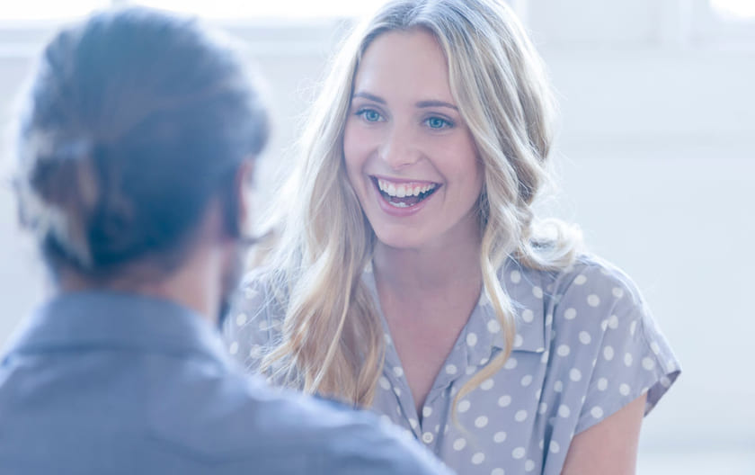 Kvinne med blondt hår smiler til mannlig kollega. Illustrasjon til sak om å lykkes med HR for Lederne