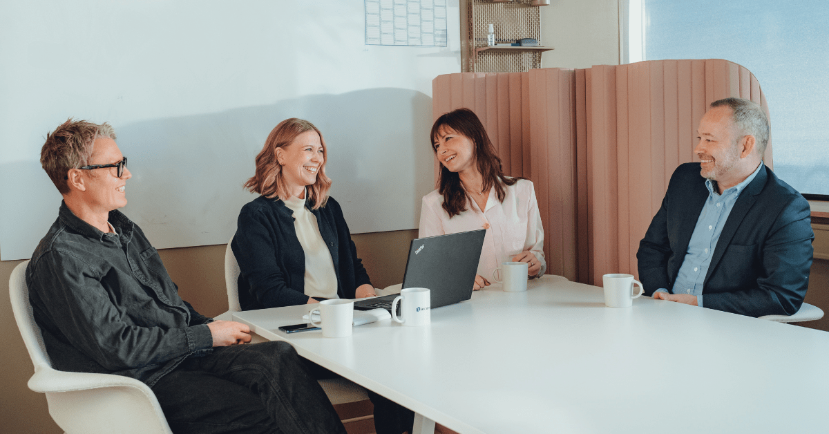 To glade kvinner og to menn i et møterom