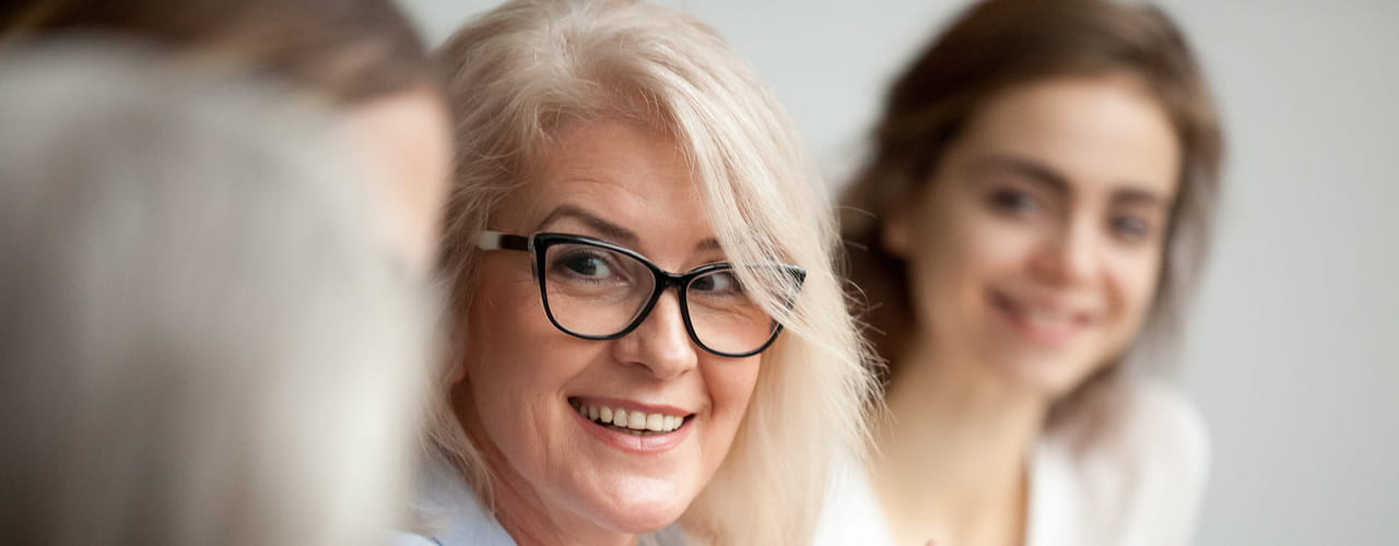 En dame smiler til en annen i et møte.
