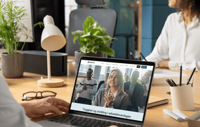 To personer sitter på kontor, og Ledernes hjemmeside vises på pc