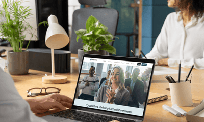 To personer sitter på kontor, og Ledernes hjemmeside vises på pc