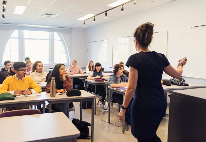 En lærer står foran sittende videregående-elever i et klasserom. Bilde.