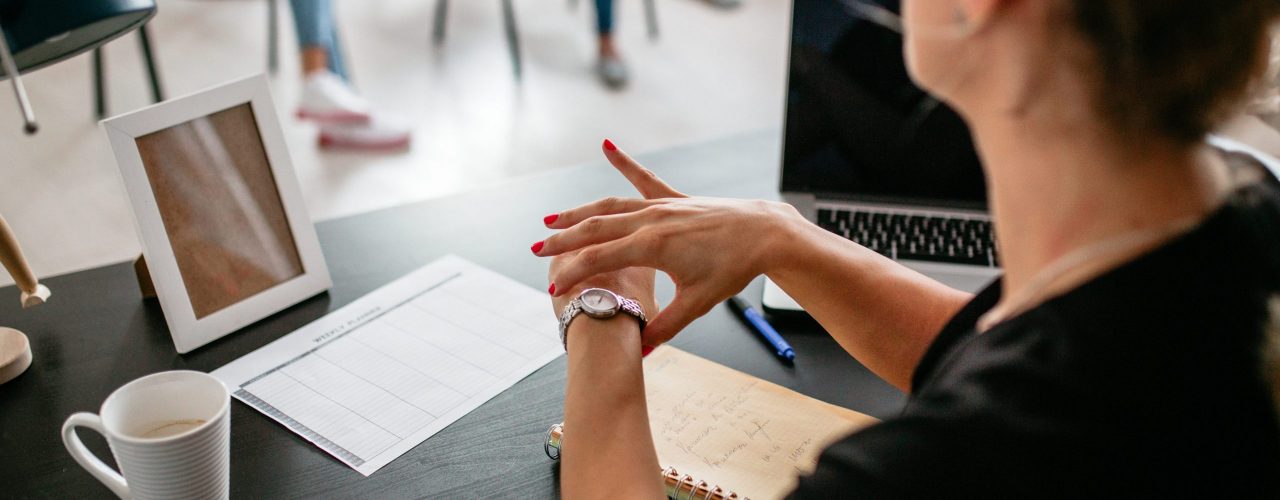 En lærer ser på armbåndsuret sitt i klasserommet. Bilde.