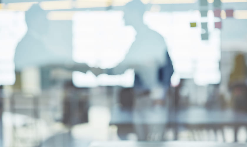 To personer håndhilser på et kontor. Bilde.