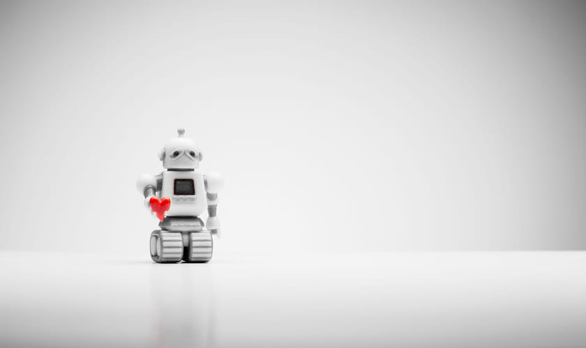 Liten lekerobot holder et rødt hjerte. Bilde.