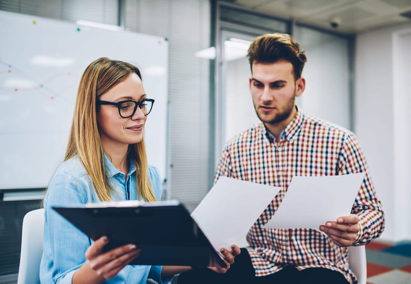 To lektorer ser på noen ark i et klasserom. Bilde.