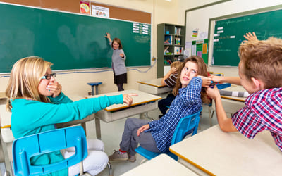 En elev trekker i en annen elevs arm i et klasserom. Illustrasjonsfoto.